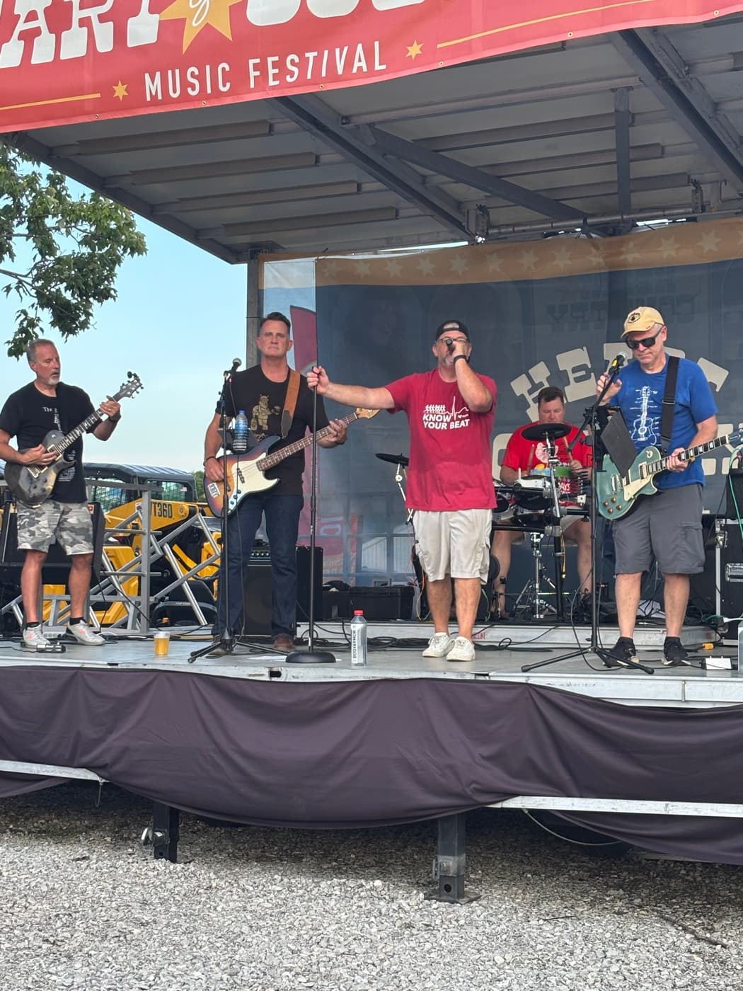 Singer and guitarists at the front of the Kenton County Fair stage, drummer behind them