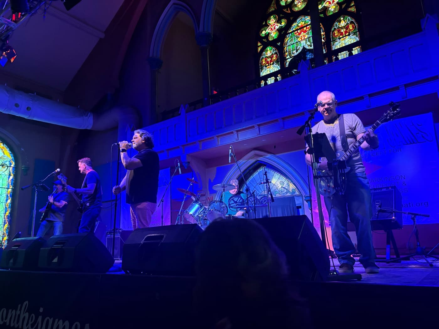 PHEVE on stage under blue light at Rock on the James, stained glass windows behind the band